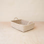 The LIKHA Abaca Rectangle Tray with Handles, handwoven by Filipino artisans from sustainable abaca fiber, rests on a light wooden surface against a neutral beige background.