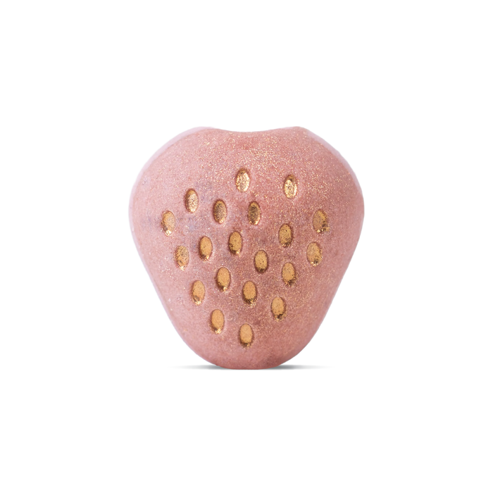 The Strawberry & Basil Bath Bomb by Pacha Soap Co. is a pink, strawberry-shaped soak with gold dots and a shiny finish—infused with plant oils—shown against a white background.