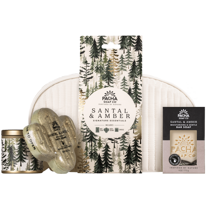 Pacha Soap Co. Essentials Bath Gift Set including an amber fragrance sandalwood candle, a cactus-shaped bath bomb, a boxed bar of soap, and a tall gift card, arranged in front of a white zippered pouch.