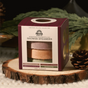 A square box of the Pacha Soap Co. Shower Steamer Set - Heritage Holiday Collection, featuring Vanilla Bean & Clove, Frankincense & Amberwood, Pomegranate & Orange Peel, and Balsam & Pine scents, resting on a wood slice.