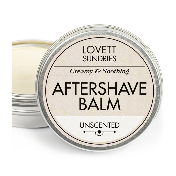 An open metal tin of Lovett Sundries Aftershave Balm is shown, labeled as Unscented and promising to prevent razor burn. Inside, the creamy, natural balm is visible.