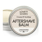 An open metal tin of Lovett Sundries Aftershave Balm is shown, labeled as Unscented and promising to prevent razor burn. Inside, the creamy, natural balm is visible.