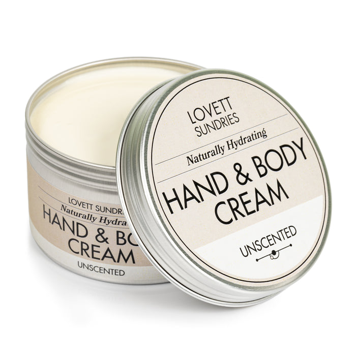 A silver tin with a beige label showcases Lovett Sundries Hand & Body Cream, emphasizing its rich hydration as a skin moisturizer. The lid is ajar, revealing the unscented cream inside.