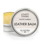 A tin of Lovett Sundries Leather Balm with a partially open lid reveals yellow conditioner inside. The white label displays Seal & Condition and All Natural.
