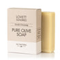 A beige box labeled Lovett Sundries Pure Olive Oil Soap sits next to a yellowish bar. The packaging notes it is all-natural, gently cleansing, and ideal for sensitive skin, offering moisture and protection.