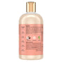 A transparent plastic bottle with a gold cap showcases SheaMoisture Shampoo - Curl + Shine, accented by a peach label. The text highlights key ingredients—coconut oil, silk protein, and neem oil—in addition to a detailed ingredient list and the product story. This curly hair shampoo is an excellent choice for those looking to benefit from nourishing coconut and hibiscus formula.