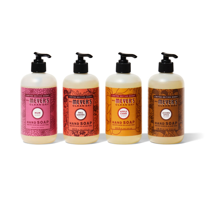 Mrs. Meyers Fall Hand Soap Collection—four bottles in seasonal scents with pump tops—are lined up against a crisp white background.