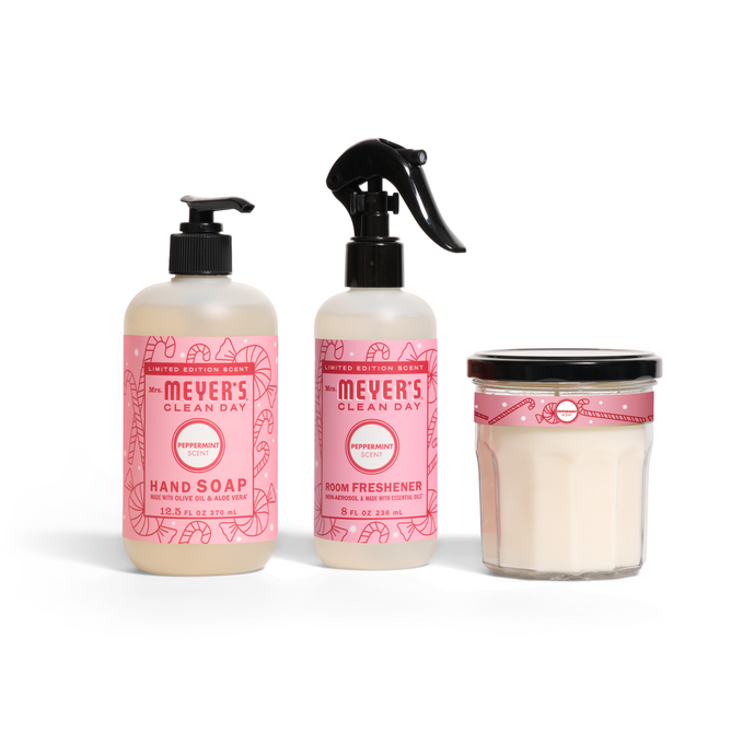 The Mrs. Meyer’s Home for the Holidays Set includes a peppermint-scented hand soap, room spray, and white candle in a glass jar—each with festive pink holiday labels.