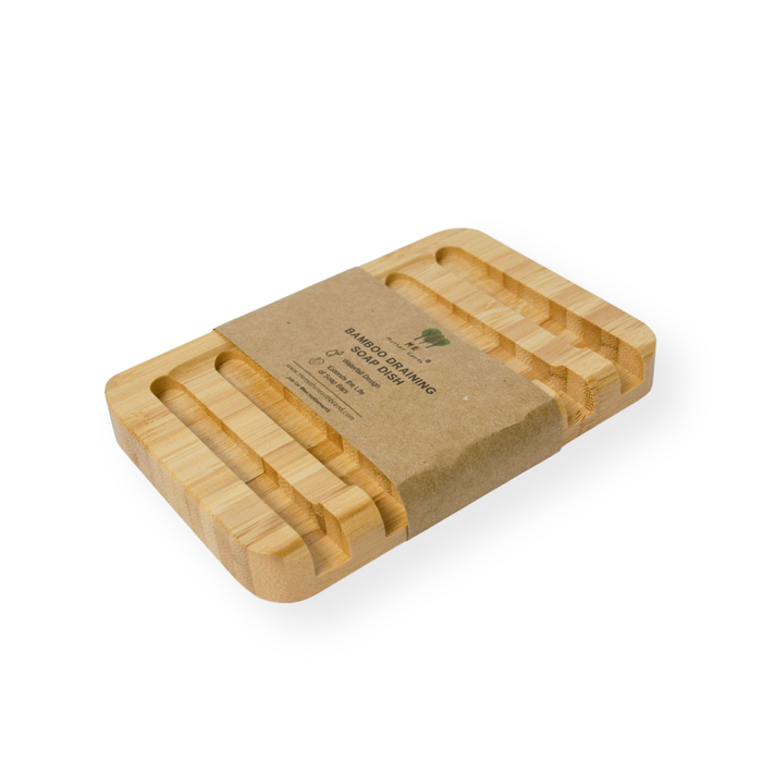 The Me Mother Earth Bamboo Draining Soap Dish features grooved slots for self-draining and comes wrapped in a brown paper band with product info, shown on a white background.