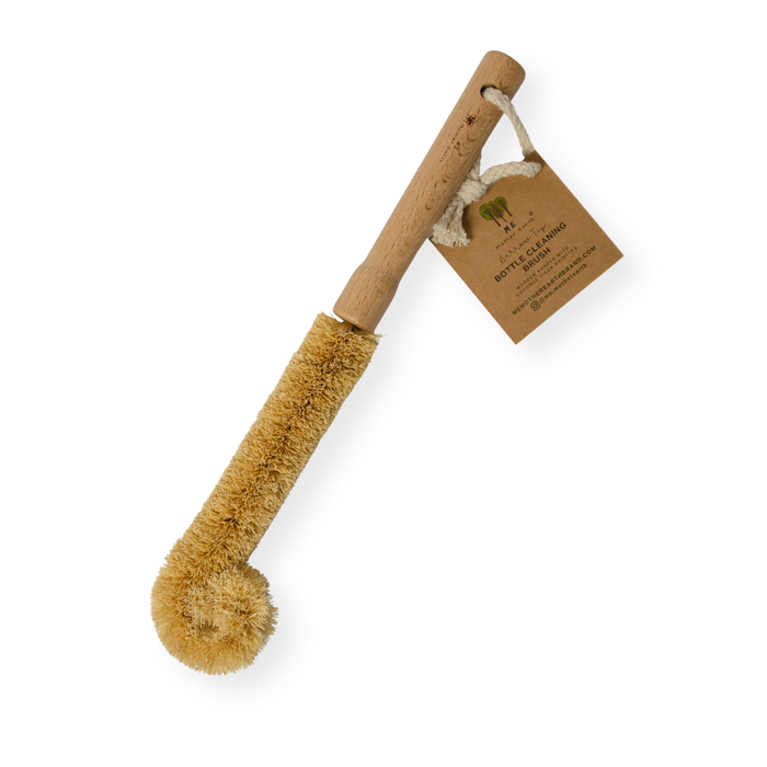 The Me Mother Earth Coconut Bottle Cleaning Brush features a wooden handle, curved head with coconut husk bristles, eco-friendly cleaning, a hanging rope, and comes with a brown paper tag.