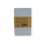 A gray notebook appears with a brown recycled paper band displaying text, a barcode, and a recycling symbol—its eco-friendly vibe echoes the Me Mother Earth Quick-Dry Diatomite Soap Dish (Face + Body). The background is plain white.