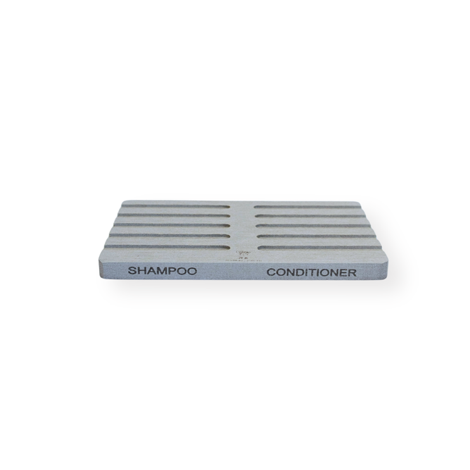 The Me Mother Earth Quick-Dry Diatomite Soap Dish is a rectangular, gray holder with ridges and two labeled sections—SHAMPOO and CONDITIONER—making it ideal for organizing shampoo bars. Displayed on a white background.