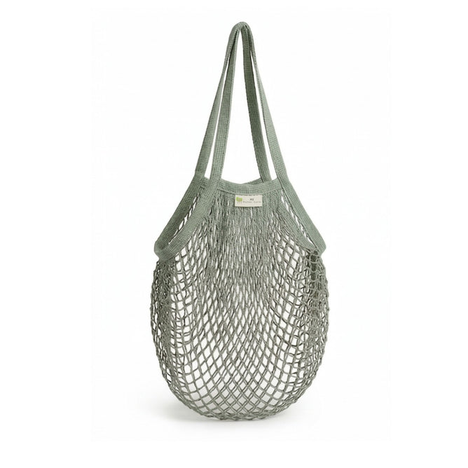 The "One Tripper" Expandable Mesh Market Bag by Me Mother Earth is a sage-green reusable grocery bag with two long handles. Made from soft, flexible netting, it’s ideal for eco-friendly shopping and shown empty against a white background.