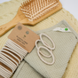 Me Mother Earth's Hair Ties made from cotton and natural rubber, a wooden hairbrush, and textured towels in soft beige and green are arranged neatly on a flat surface, highlighting sustainable personal care items.