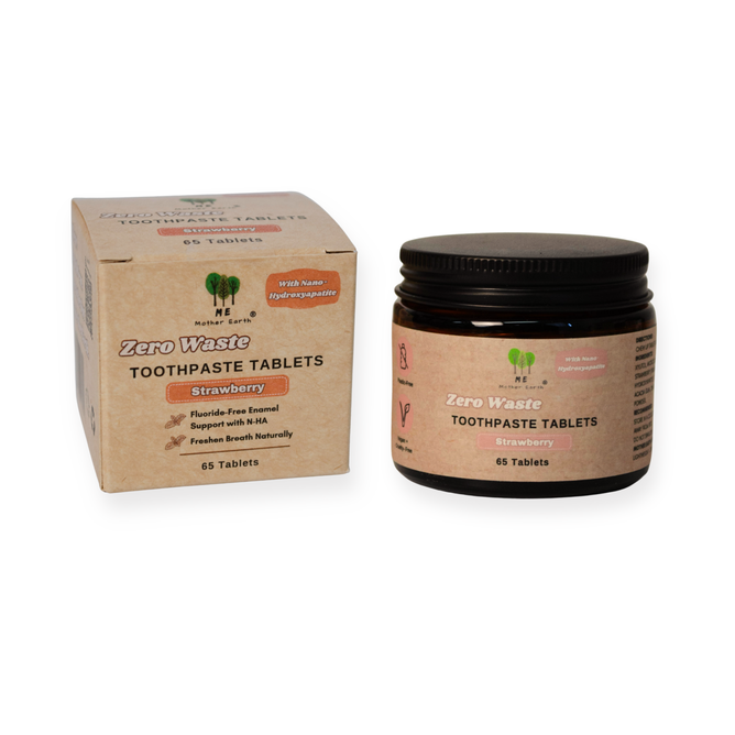 A box and a jar of Me Mother Earth Toothpaste Tablets in Amber Glass Jar - Fluoride-Free are displayed side by side. This plastic-free, vegan, naturally flavored toothpaste contains 65 travel-friendly tablets per container.
