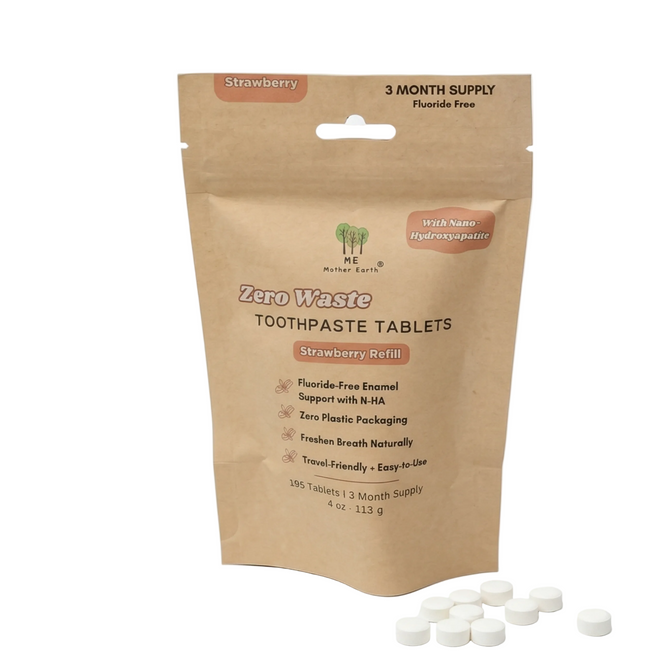 A brown resealable Me Mother Earth pouch labeled "Toothpaste Tablets 3 Month Refill - Fluoride-Free" with white tablets scattered in front; the plant-based, eco-friendly packaging highlights a strawberry flavor and zero waste.