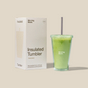 A green Morning Made Insulated Tumbler with a straw, filled with a green drink as a coffee alternative, sits beside its white “Insulated Tumbler” packaging on a beige background.