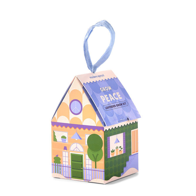 A vibrant house-shaped box labeled “Home Grown Ornaments” by Modern Sprout, adorned with a blue ribbon handle, illustrated windows, plants, and peace symbols—this festive kit is the ideal way to cultivate tranquility while adding charm to any space.