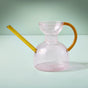 The Modern Sprout Handcrafted Borosilicate Glass Watering Can features a transparent round body with a yellow handle and spout, ideal for plant propagation, shown against a light green background.