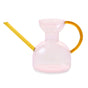 The Handcrafted Borosilicate Glass Watering Can by Modern Sprout features a translucent pink body, wide opening, yellow spout and handle—ideal as a plant propagation vessel or stylish flower vase.