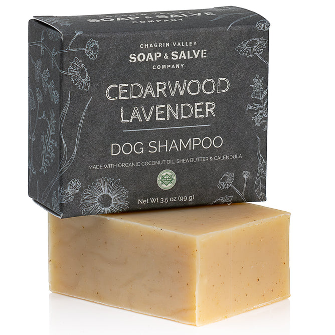 A rectangular beige bar of Chagrin Valley Soap & Salve Dog Shampoo rests before a black box featuring the brand name, product details, and botanical illustrations.