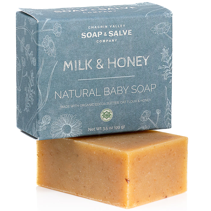 A bar of Chagrin Valley Soap & Salve Natural Baby Soap sits in front of its blue box with white text and botanical illustrations.