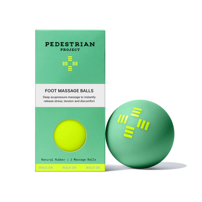 A green box labeled Pedestrian Project Foot Massage Balls stands beside a green ball with yellow markings; the packaging reveals one ball through a circular cutout, ideal for foot relaxation and stress relief.