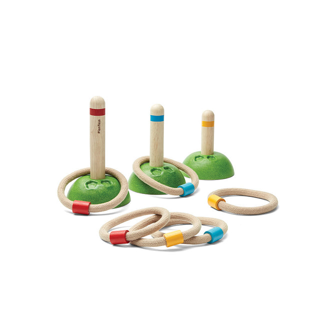 The PlanToys Wooden Meadow Ring Toss Action Game features three green-based stands with colorful stripes and six matching rope rings, encouraging sustainable active play. Set is displayed on a plain white background.