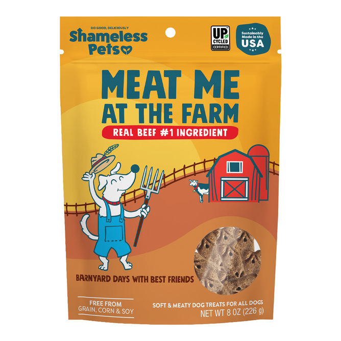 A package of Shameless Pets Dog Treats labeled Meat Me At The Feast, featuring a cartoon dog holding a pitchfork near a barn and a cow. The product highlights real beef as the main ingredient.