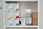 A shelf with boxes, a spray bottle, and Meliora Laundry Powder Refill for eco-friendly laundry.