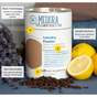 A Meliora Laundry Powder Canister, an eco-friendly detergent, sits with lemons, cloves, and folded towels. Callouts show its plastic-free packaging, complete ingredient list, and ultra-concentrated formula.