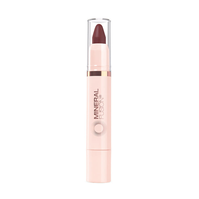 A Mineral Fusion Sheer Moisture Lip Tint with a light pink tube, clear cap, and twist-up hydrating dark mauve color exposed at the top. Mineral Fusion is printed vertically on the naturally derived tube.