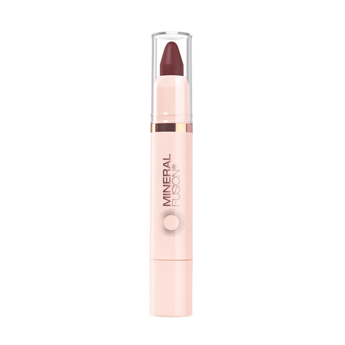 A Mineral Fusion Sheer Moisture Lip Tint with a light pink tube, clear cap, and twist-up hydrating dark mauve color exposed at the top. Mineral Fusion is printed vertically on the naturally derived tube.