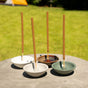 Four Murphys Naturals Ceramic Incense Stick Holders, each with a long incense stick, are arranged on a round outdoor table with green grass and a tent in the background—ideal for outdoor pest control.