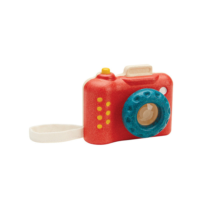 PlanToys’ My First Wooden Toy Camera for Toddlers features a vibrant red body, blue textured lens, yellow buttons, and a white wrist strap—ideal for kids who love eco-friendly play.