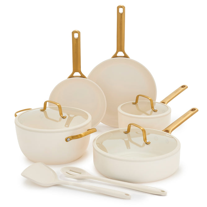 The GreenPan Reserve Pro Cookware Set features cream-colored ceramic nonstick pans with gold handles: two frying pans, a saucepan, sauté pan, Dutch oven, matching lids, spatula, and spoon. PFAS free and elegantly displayed on a white background.