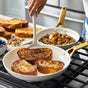 A person cooks three slices of French toast in a GreenPan Reserve Pro Cookware Set frying pan, with caramelized fruit in another pan and extra toast, berries, and nuts on the counter nearby.