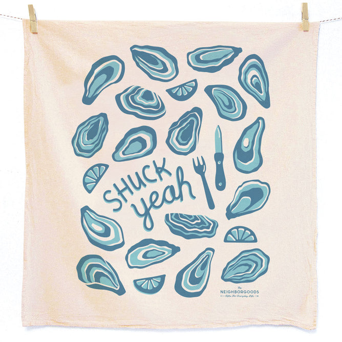 The Neighborgoods Dish Towel features blue oyster shells, lemon wedges, a fork, and an oyster knife on beige unbleached cotton. “SHUCK yeah” pops at the center. Absorbent, hand-packaged in the USA.