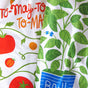 The Neighborgoods Dish Towel Set features a colorful print of tomato plants, green leaves, red and yellow tomatoes, “TO-MAY-TO, TO-MAH-TO” text, and a basil plant in a blue pot—perfect for brightening your kitchen.