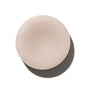 A round, light beige solid object, The Fixer Conditioner by NOTICE Hair Co, a plastic-free bar for repairing damaged hair, is shown on a white background with a soft shadow on the right.