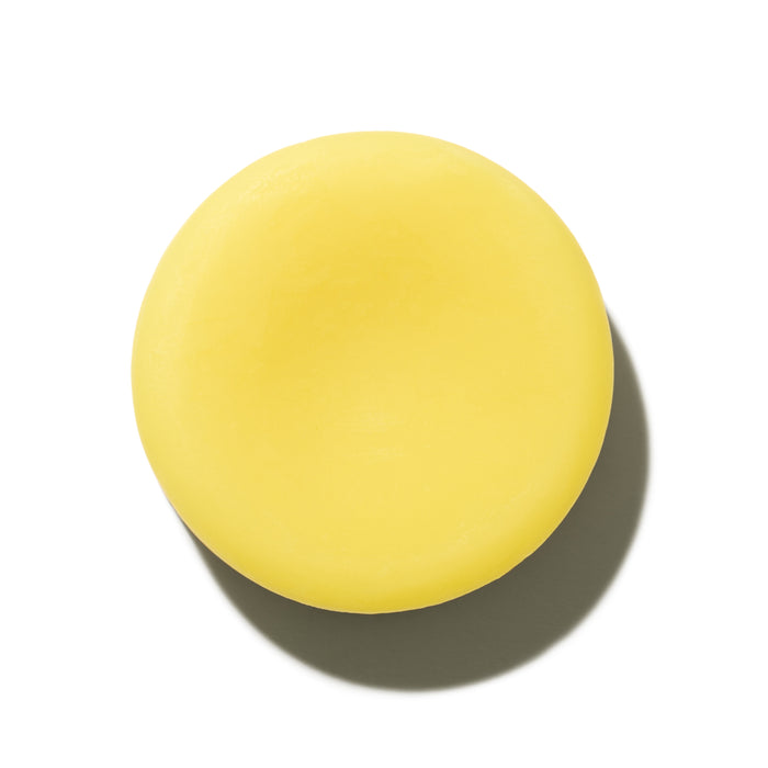 A round, solid yellow Sorrento Conditioner Bar by NOT!CE Hair Co is pictured on a white background with a shadow to the right—a perfect plastic-free hair care solution.