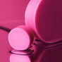 Two round, solid pink ALINE Mini Conditioner Bars by NOT!CE Hair Co are shown on a glossy pink surface—one large and one mini sample—both smooth and softly reflected, ideal for vegan hair care and taming frizz.