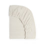 The Organic Breathable Muslin Crib Sheet by Naturepedic, shown in cream, features soft organic cotton and a snug elastic edge partially wrapped around a mattress against a white background.