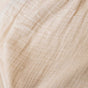 Close-up of light beige, crinkled fabric featuring subtle grid-like lines—ideal for Naturepedic Organic Breathable Muslin Crib Sheets, made from GOTS certified organic cotton for soft comfort and exceptional breathability.