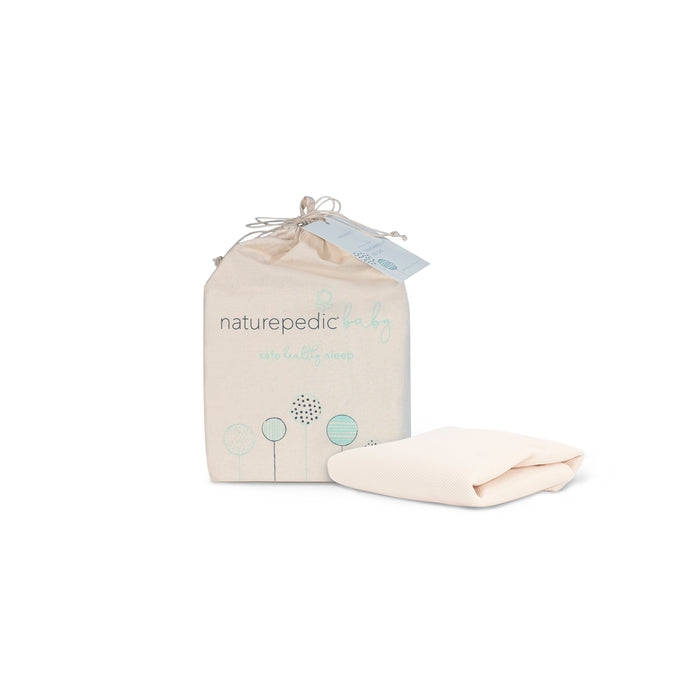 A Naturepedic Breathable Crib Mattress Cover with cream packaging featuring minimalist tree designs sits next to a folded organic cotton crib cover, both displayed on a white background.