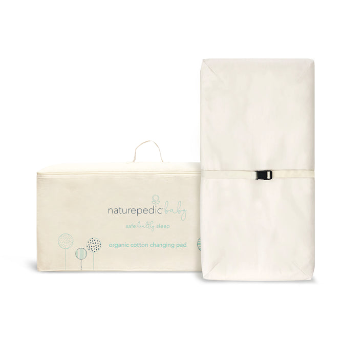 The Naturepedic Organic Cotton Changing Pad, shown with its cream packaging featuring light blue text and illustrations, is rectangular, white, includes a safety strap, and measures 16.5 x 31.5 x 4 inches.