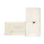 The Naturepedic Organic Cotton Changing Pad, shown with its cream packaging featuring light blue text and illustrations, is rectangular, white, includes a safety strap, and measures 16.5 x 31.5 x 4 inches.