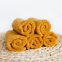 Five Natemia Organic Super Absorbent Washcloths, made from 100% GOTS Certified organic cotton, are rolled and neatly stacked in a pyramid on a natural-colored woven mat against a light background.