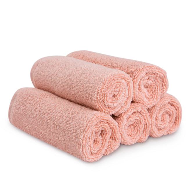 Five neatly rolled, light pink Natemia Organic Super Absorbent Washcloths made from 100% GOTS Certified Organic Cotton are stacked in a pyramid shape on a white background.