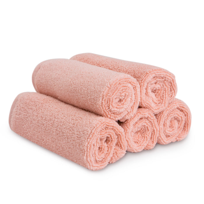 Five neatly rolled, light pink Natemia Organic Super Absorbent Washcloths made from 100% GOTS Certified Organic Cotton are stacked in a pyramid shape on a white background.